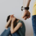 Man Clenching Fist Near a Woman Covering Face While Sitting