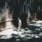 boy wearing white top standing on gray concrete floor
